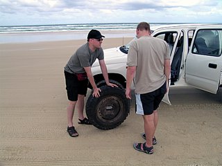 Changing the front left tyre of our Toyota 4 WD on the beach of Fraser Island.
